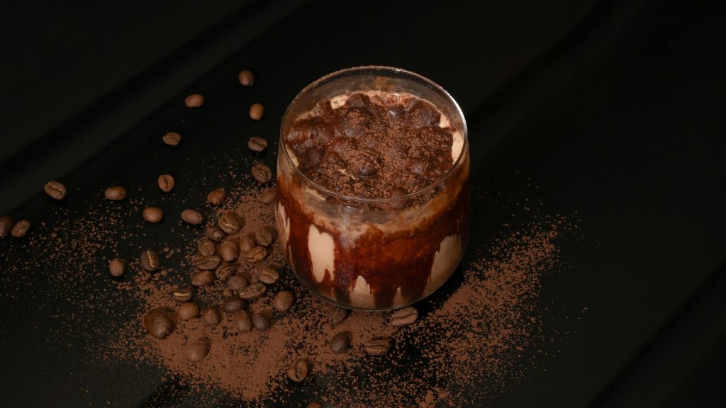 Delicious coffee dessert topped with chocolate and cocoa on dark background.